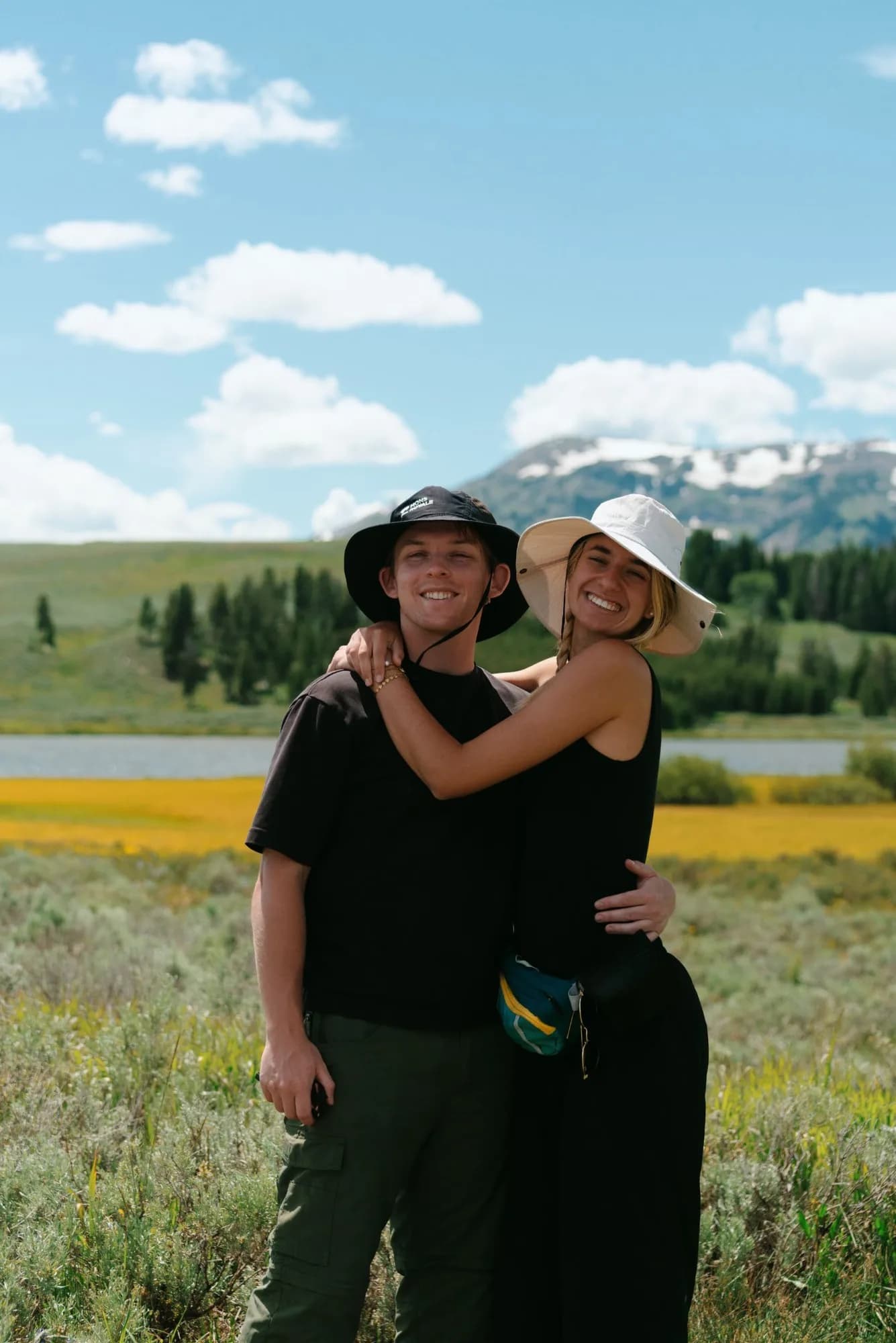 Ben and his partner on a hike, a mountain lake and snow-capped peak behind them